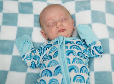 A newborn asleep on a blanket.