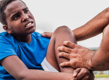 Child athlete with injured knee on field
