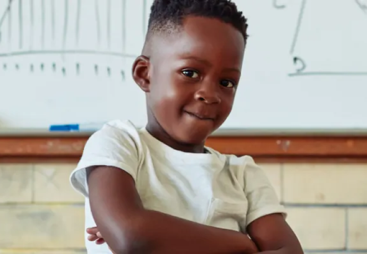 Boy crossing his arms in front of a whiteboard