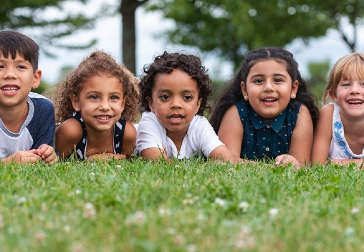Kids laying down in the grass in a line