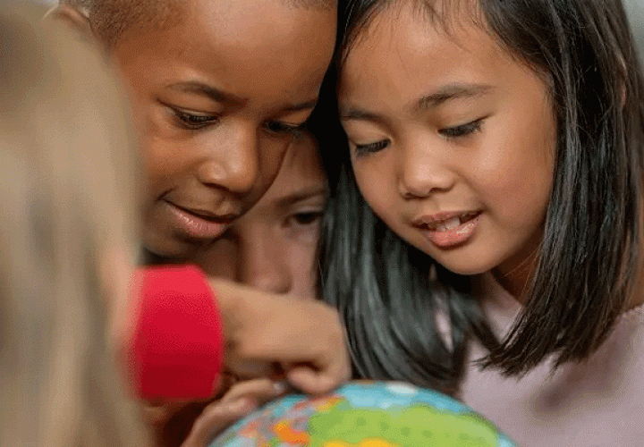Groups of kids looking at a globe