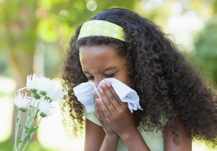 A young girl blows her nose