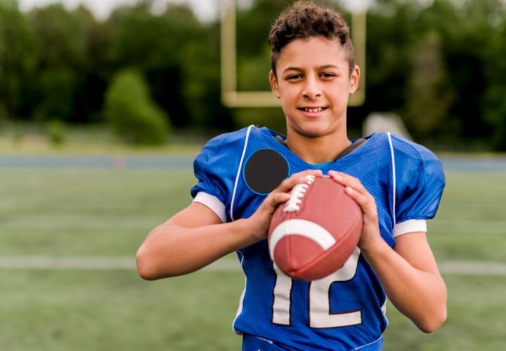 Young boy in a football jersey holding a football