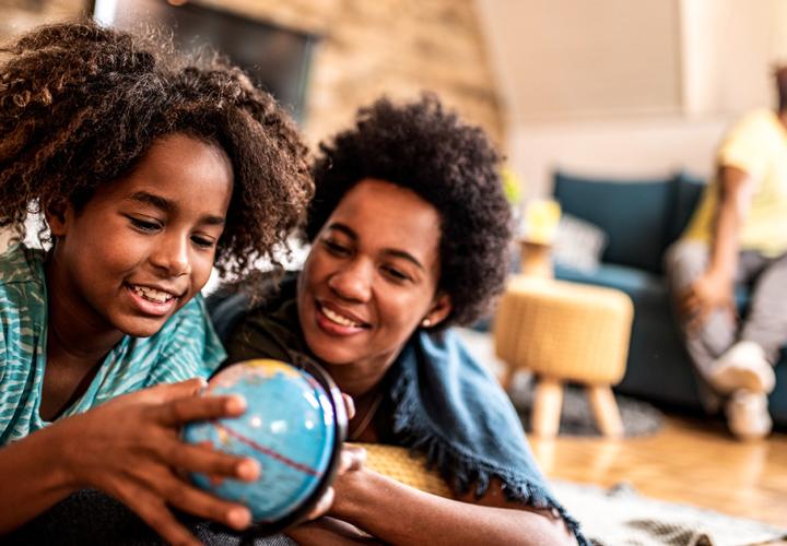 A mother and daughter look at a globe