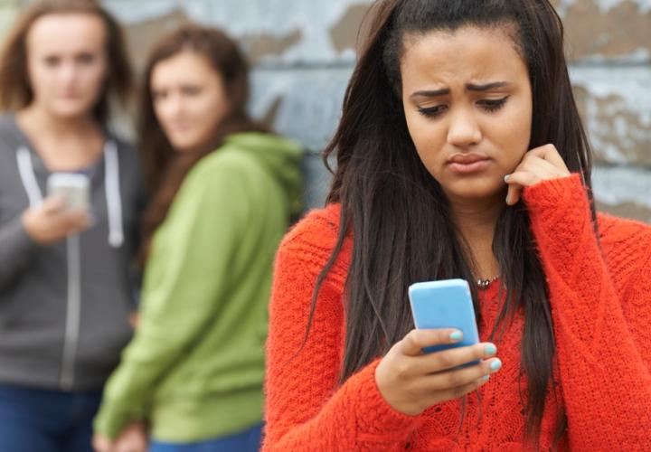 A young teen looks at her phone sadly