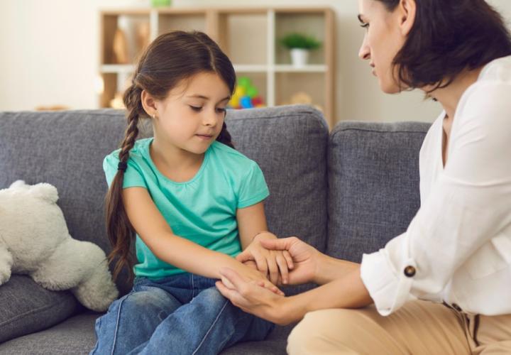 Mother sitting with daughter holding her hands