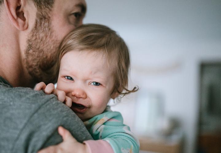 A dad holds his crying toddler