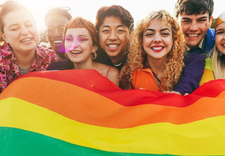 A group of friends hold a pride flag