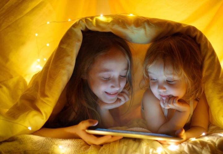 Two young girls hide under a blanket