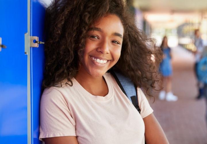 A young girl smiles and leans against her locker