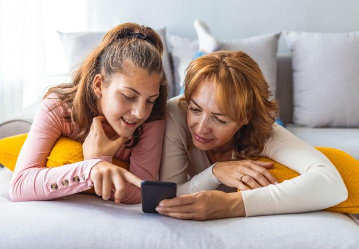A mother and daughter look at a phone