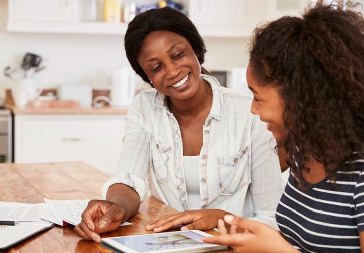 A mother and daughter look at a tablet