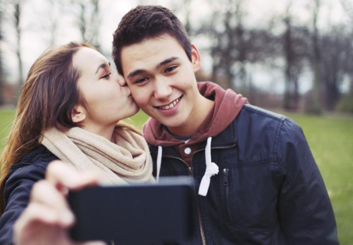 A girl kissing her boyfriend on the cheek