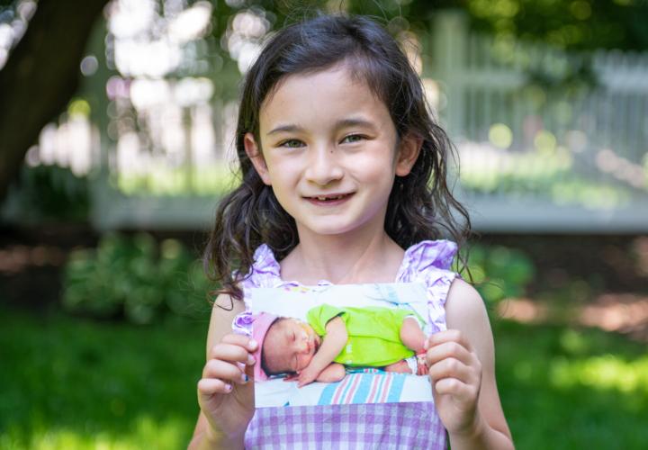 Claire holding a baby photo of herself