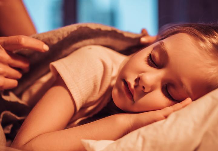 Young girl being tucked into bed