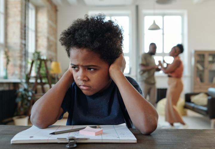 School boy stressed, sitting at desk, doing homework