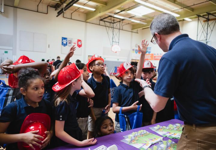 School-aged kids holding red safety hats at gun safety conference