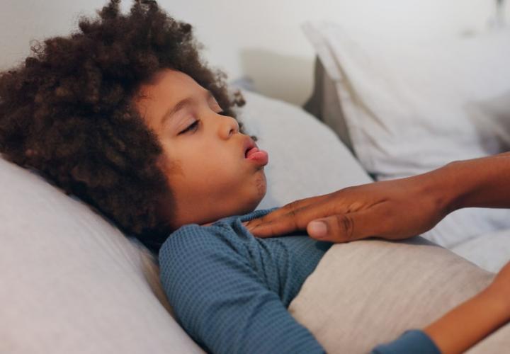 boy coughing in bed, mom's hand on chest