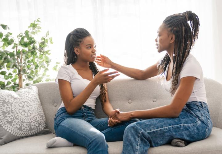 mother and teenage daughter sitting on couch talking maybe about breast reduction surgery