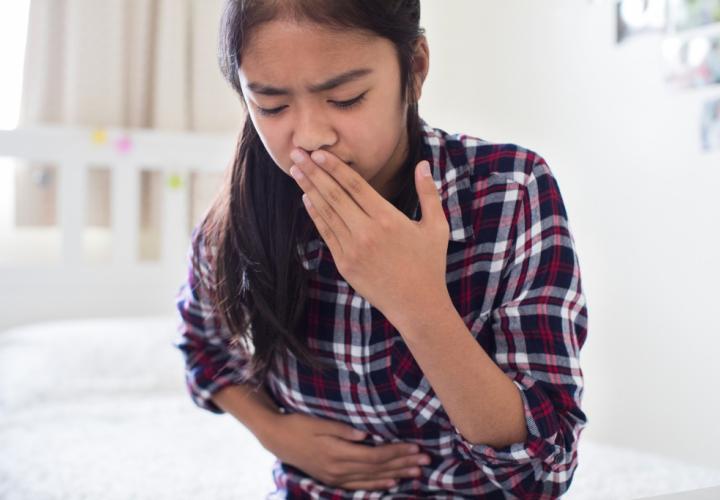 Young girl sitting on bed feeling nauseous