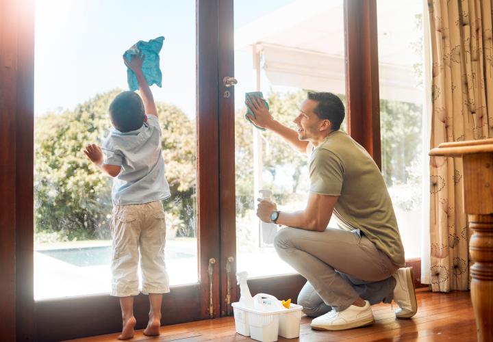 A father and son cleaning a window together.