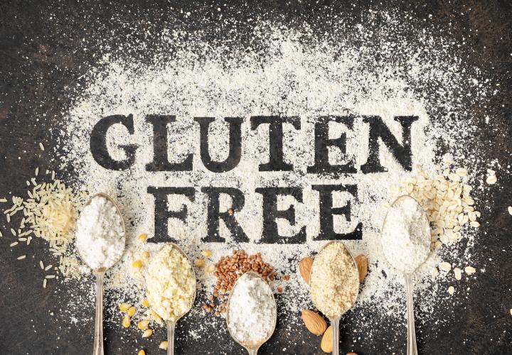 Gluten Free written on table of flour surrounded by spoons