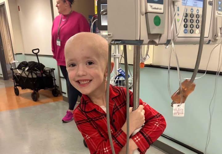 Nico in red pajamas going for a ride on the medical equipment