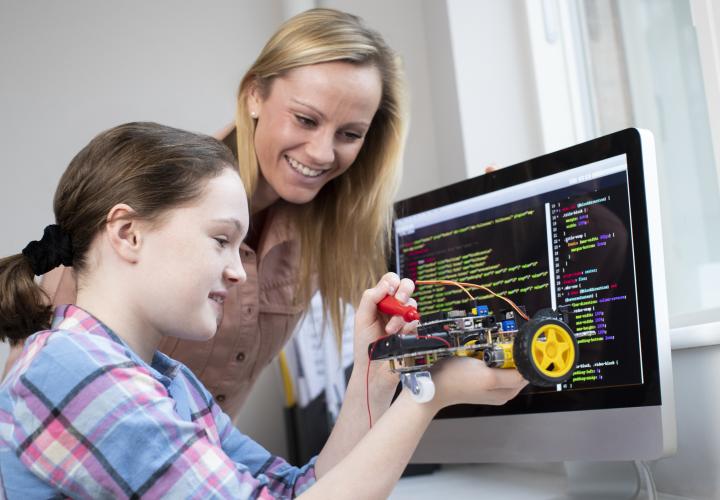 Teacher with middle school aged girl, building robot, mental health tips for caregivers and school staff