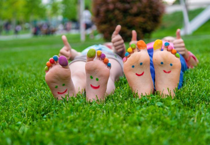hildren's feet with a pattern of paints smile on the green grass