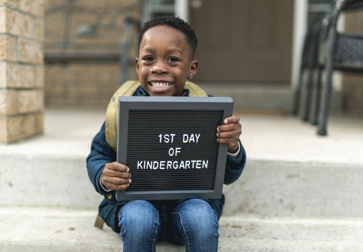 Child on his first day of school holding sign