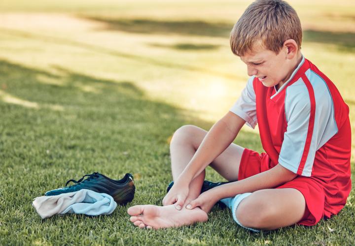 young soccer player with heel pain on field