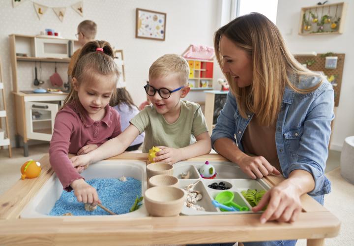 Mother playing on sensory table with two young children