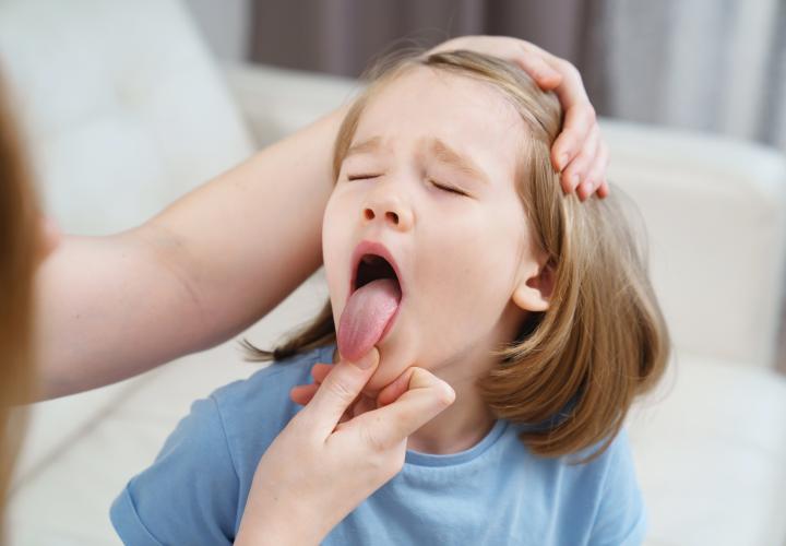 Young girl getting throat checked, tongue out