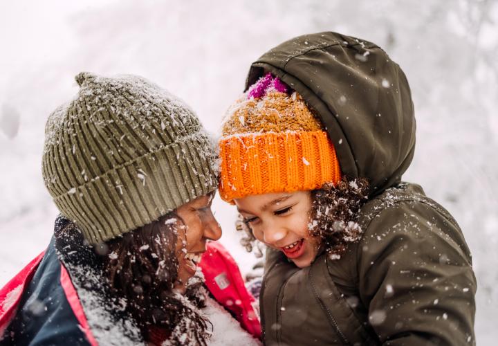 A mom and daughter playing in the snow together