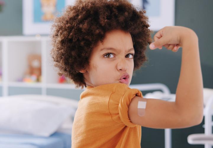Young boy proudly lifts arm after receiving vaccine