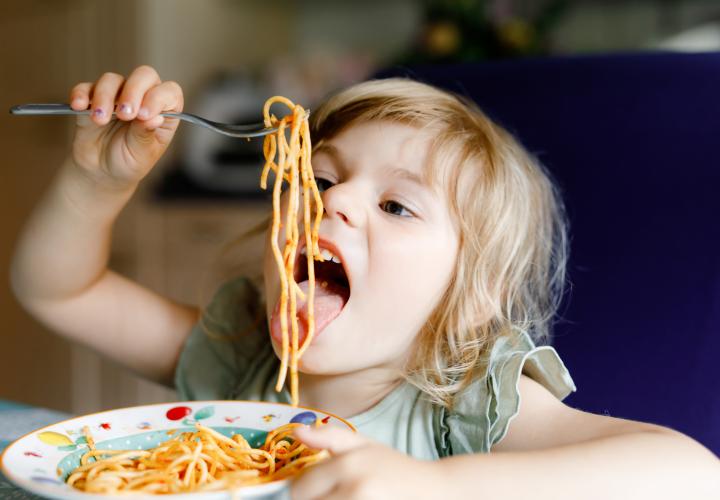 Young girl eating spaghetti happily