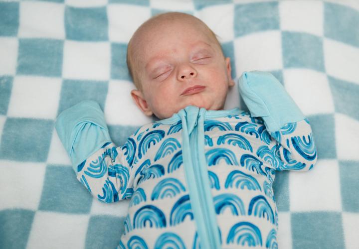 A newborn asleep on a blanket.