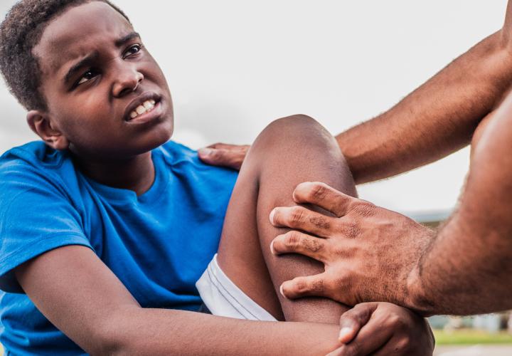 Child athlete with injured knee on field