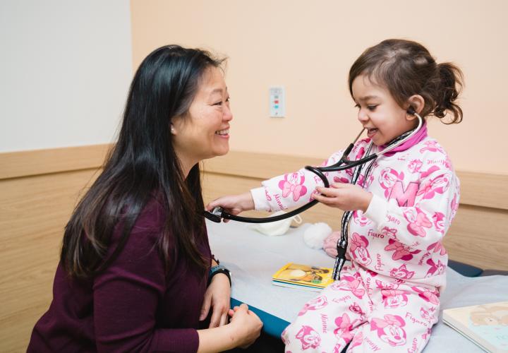 Child uses stethoscope to check provider's heart