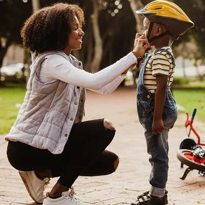Mom fastening a bike helmet on a child