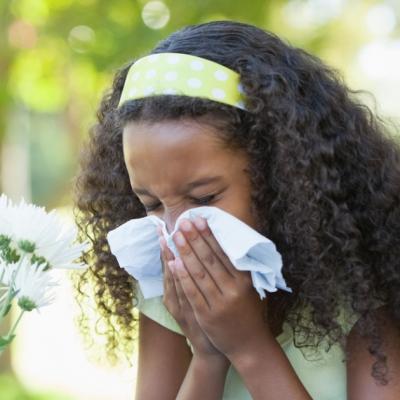 A young girl blows her nose