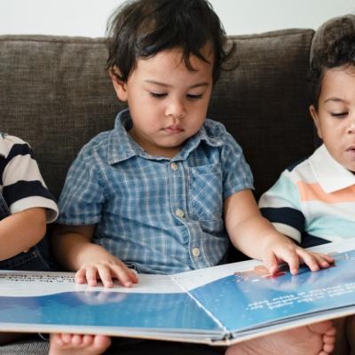 3 toddlers look at a book