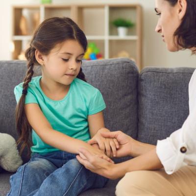 Mother sitting with daughter holding her hands