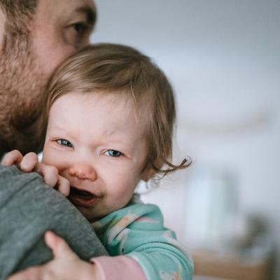 A dad holds his crying toddler
