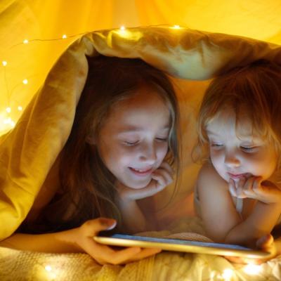 Two young girls hide under a blanket
