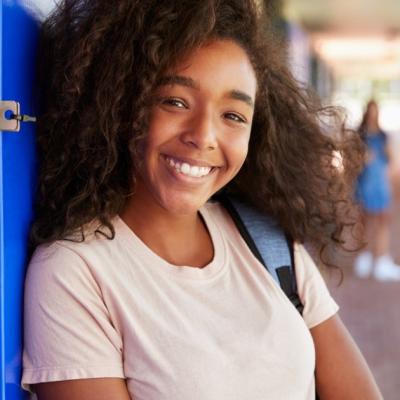 A young girl smiles and leans against her locker