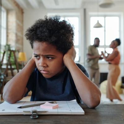 School boy stressed, sitting at desk, doing homework