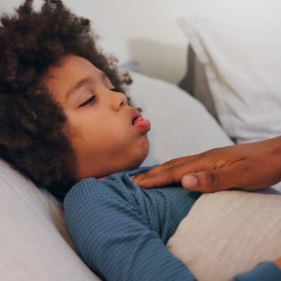 boy coughing in bed, mom's hand on chest