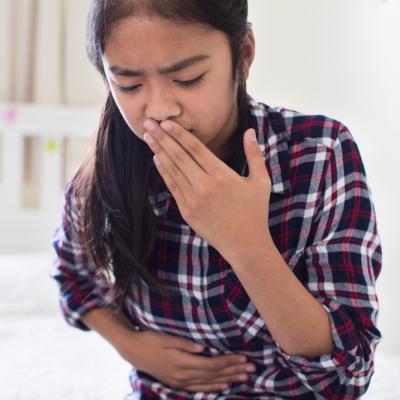Young girl sitting on bed feeling nauseous