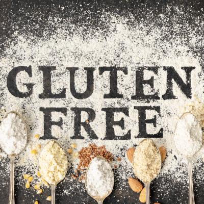 Gluten Free written on table of flour surrounded by spoons